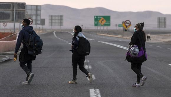 Los migrantes venezolanos Reinaldo (izquierda), Anyier (derecha) y su hija Danyierly, 14, caminan por la carretera camino a Iquique, luego de cruzar desde Bolivia, el 18 de febrero de 2021. (Foto de MARTIN BERNETTI / AFP).