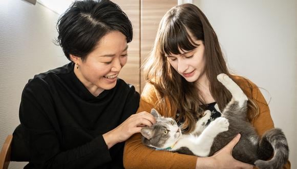 Esta foto tomada el 30 de octubre de 2022 muestra a Miki (izquierda) y su pareja Katie interactuando con su gato luego de una entrevista con AFP en su casa en Tokio.  (Foto de Yuichi YAMAZAKI / AFP)
