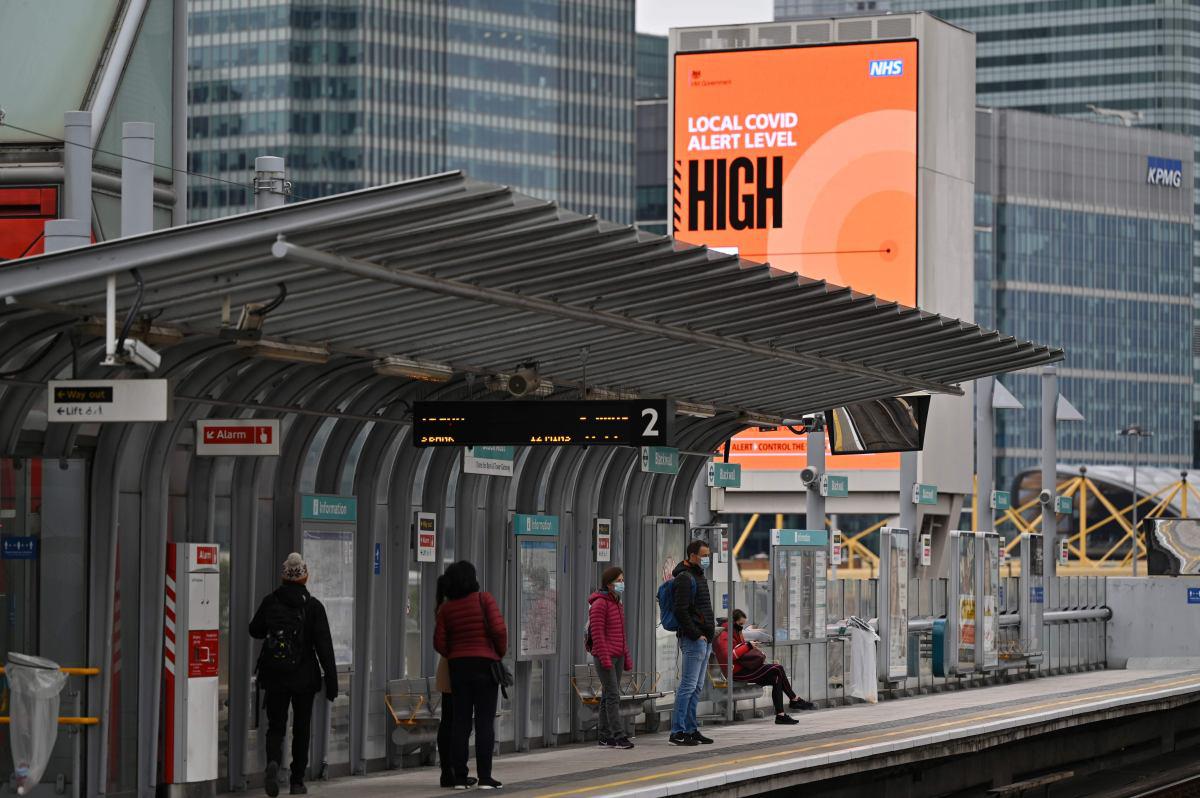 La gente espera un tren mientras se observa un letrero con el mensaje de nivel de alerta de coronavirus "ALTO", en el este de Londres, Inglaterra. (AFP / JUSTIN TALLIS).