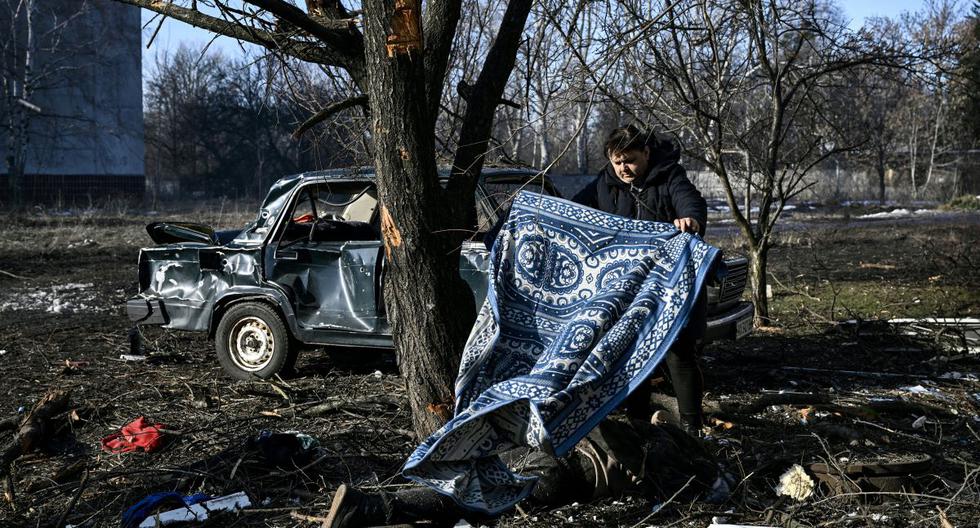 Un hombre cubre un cuerpo tendido en el suelo después de los bombardeos de Rusia en la ciudad de Chuguiv, en el este de Ucrania, el 24 de febrero de 2022. (ARIS MESSINIS / AFP).
