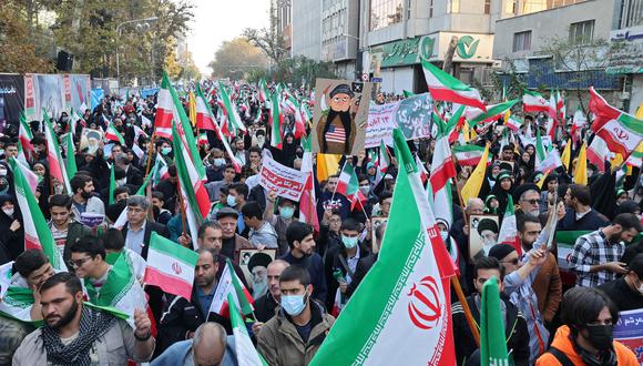 Los iraníes ondean las banderas nacionales de su país mientras participan en una manifestación frente a la antigua embajada de los Estados Unidos en la capital, Teherán. (Foto: ATTA KENARE / AFP)