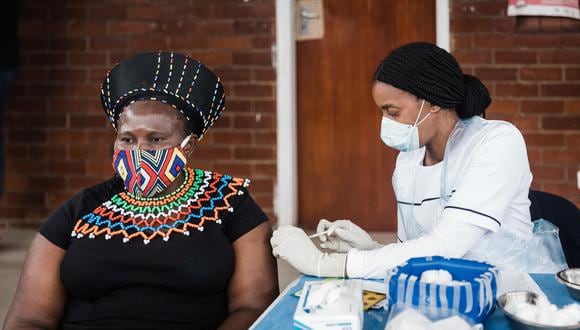 A traditionally clad woman in Zulu attire looks on as she receives a jab of the Johnson and Johnson vaccine from Sister Nomkhosi Msibi during the launch of the VaxuMzansi National Vaccine Day Campaign at the Gandhi Phoenix Settlement in Bhambayi township, north of Durban , on September 24, 2021. - The campaign launched by the Religious Forum Against Covid-19 (RFA) is an inter-faith collaboration of various religious communities standing together to fight the spread of the pandemic. The campaign aims to encourage congregations and followers to vaccinate with a sense of urgency to increase vaccine uptake. (Photo by Rajesh JANTILAL / AFP)