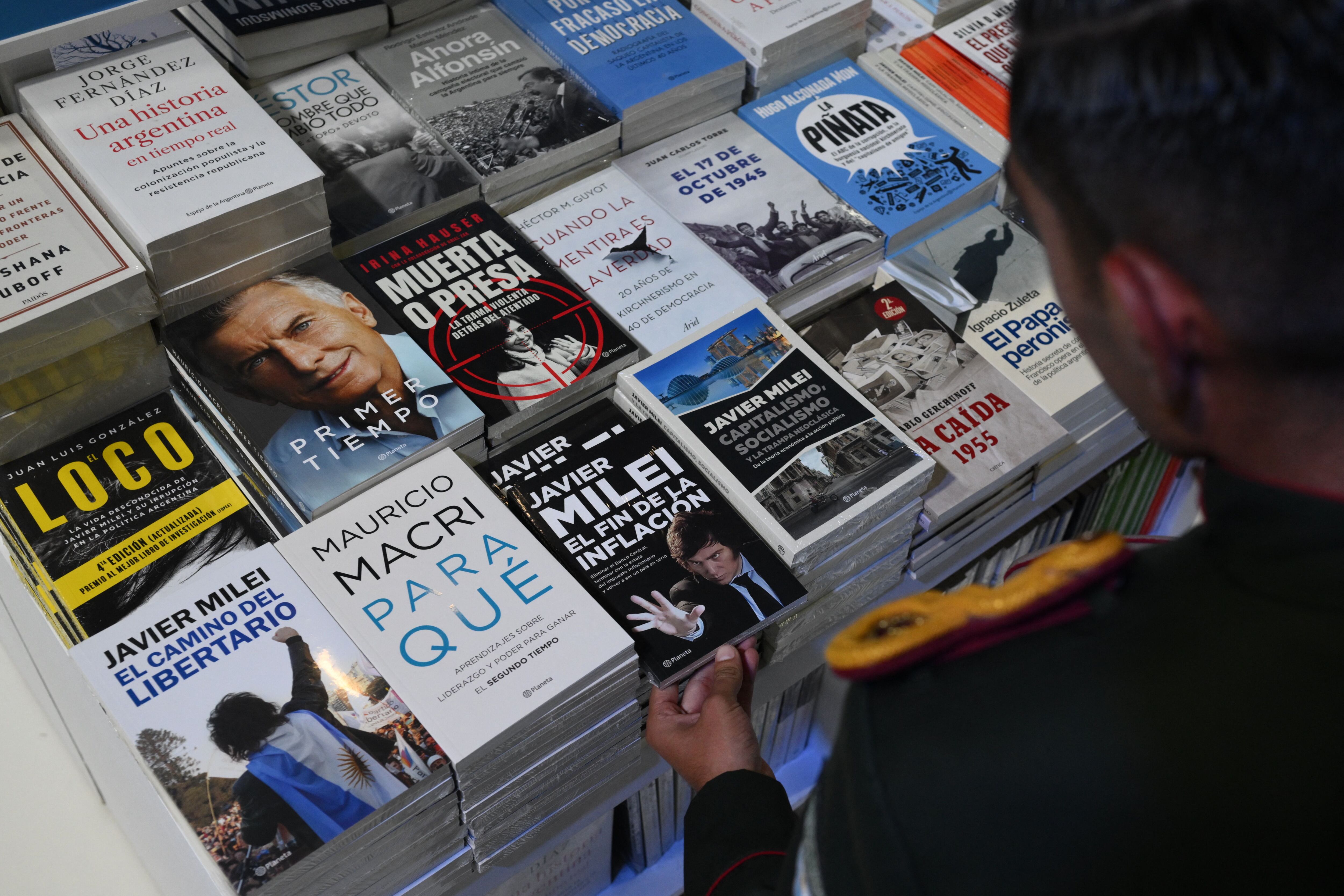 Un cadete de la Gendarmería Argentina toma una copia de un libro del presidente Javier Milei en la 48 Feria Internacional del Libro de Buenos Aires el 25 de abril de 2024. (Foto de Luis ROBAYO/AFP).