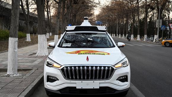 The photo taken on November 25, 2021 shows an Apollo Go autonomous taxi on a street in Yizhuang, a town of Daxing District, in the southeast suburbs of Beijing. - Beijing this week approved its first autonomous taxis for commercial use, bringing dozens of the so-called "robotaxis" to the streets of the Chinese capital. An employee of the taxi firm also sits in the front of the car in case any sudden intervention is needed, but the vehicle drives itself. (Photo by Jade GAO / AFP) / TO GO WITH AFP STORY CHINA-ECONOMY-TRANSPORT-TECHNOLOGY