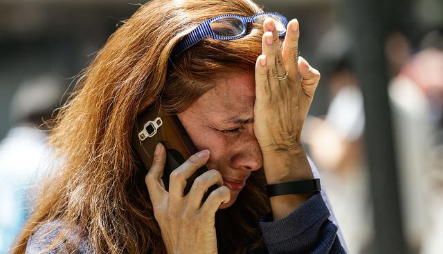 A woman cries as she tries to reach people on her cellphone after she evacuated with others to Paseo de la Reforma street after an earthquake in Mexico City, Tuesday, Sept. 19, 2017. A powerful earthquake jolted central Mexico on Tuesday, causing buildings to sway sickeningly in the capital on the anniversary of a 1985 quake that did major damage. (AP Photo/Marco Ugarte)