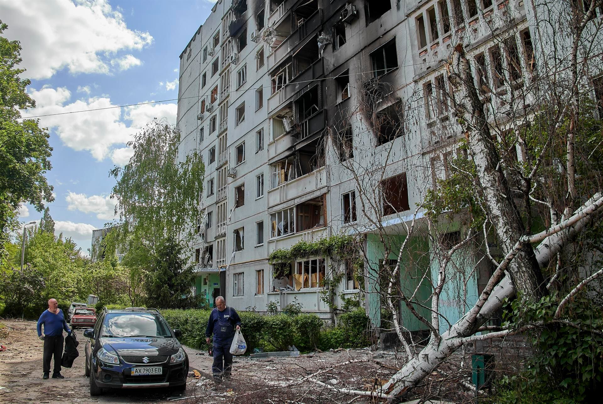 Locals take some belongings from a residential building partially destroyed by Russian bombing in the Nord Saltivka district, in Kharkiv, Ukraine, on May 23, 2022. (EFE/EPA/SERGEY KOZLOV).