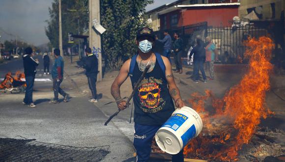 La gente protesta en medio de barricadas en llamas en demanda de ayuda económica del gobierno de Chile para hacer frente a la pandemia de coronavirus. (Foto de RAMON MONROY / AFP).