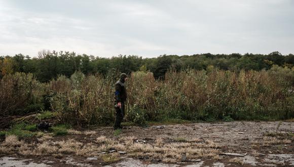 Un soldado ucraniano observa un posible campo minado cerca de una granja industrial de pollos, un área donde las fuerzas rusas estaban atrincheradas, cerca de una supuesta fosa común en Kozacha Lopan, región de Kharkiv, el 26 de septiembre de 2022 en medio de la invasión rusa de Ucrania.  (Foto de Yasuyoshi CHIBA / AFP)