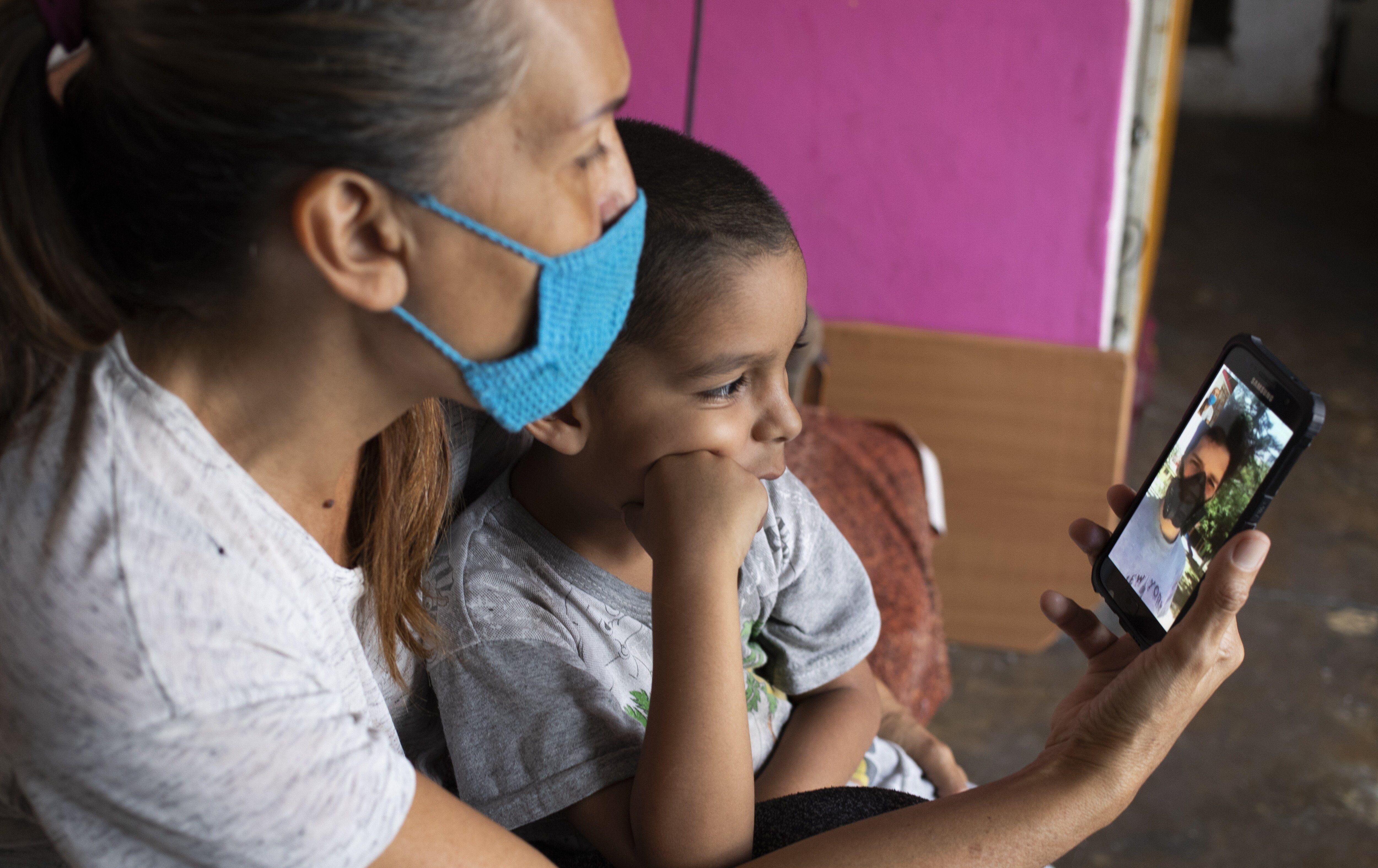 Daniel se sienta en el regazo de su abuela en su departamento en Caracas, Venezuela, mientras conversan con su padre Misael Cocho, quien migró al Perú. (Foto AP / Ariana Cubillos).