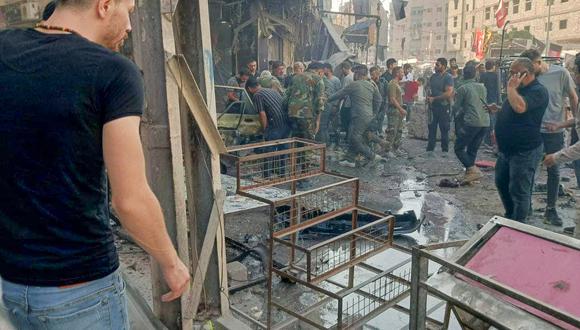 Esta imagen publicada por la televisión siria en su canal Telegram muestra a personas reunidas en el lugar de una explosión en la ciudad de Sayyida Zeinab, en las afueras de Damasco. (Foto: SYRIAN TV / AFP)