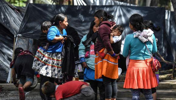 Los indígenas Embera sacan agua de una fuente en un parque de Bogotá, el 2 de octubre de 2021. Las familias indígenas Embera pasaron la noche en carpas y chozas manifestando su rechazo a las políticas dirigidas por el gobierno del presidente colombiano Iván Duque. (Foto de Juan BARRETO / AFP)