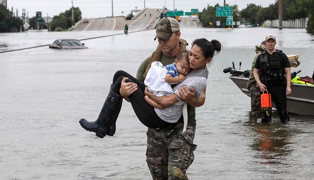 Houston Police SWAT officer Daryl Hudeck carries Connie Pham and her 13-month-old son Aiden after rescuing them from their home surrounded by floodwaters from Tropical Storm Harvey Sunday, Aug. 27, 2017, in Houston. The remnants of Hurricane Harvey sent devastating floods pouring into Houston Sunday as rising water chased thousands of people to rooftops or higher ground. (AP Photo/David J. Phillip)