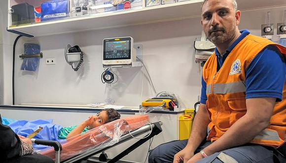 Un paramédico se sienta junto a un niño palestino herido que yace en una ambulancia en el lado egipcio del cruce fronterizo de Rafah con la Franja de Gaza, en la provincia nororiental de Sinaí del Norte, el 6 de noviembre de 2023. (Foto de AFP)