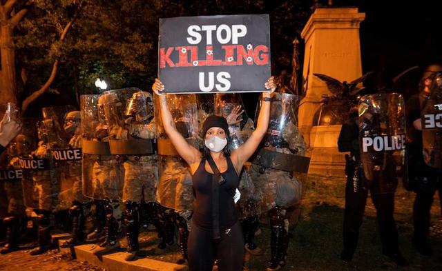 Una manifestante con una pancarta en la que se puede leer "Deja de matarnos" durante las manifestaciones en Washington por quinto día consecutivo por la muerte de George Floyd a manos de la policía de Minneapolis. (EFE/ Jim Lo Scalzo).
