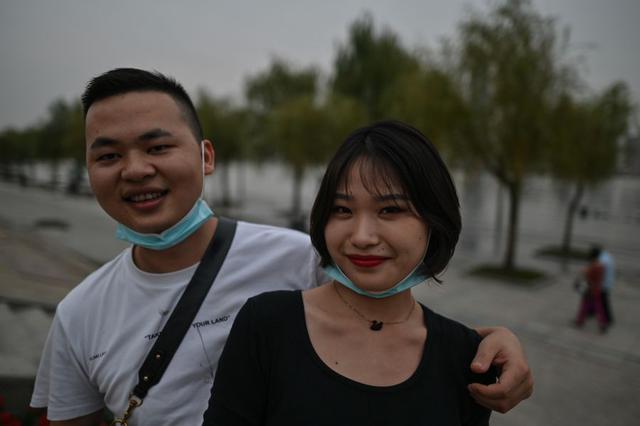 Una pareja que usa mascarillas como medida preventiva contra el coronavirus COVID-19 posa para una foto en un parque junto al río Yangtze en Wuhan, el 28 de septiembre de 2020 (Foto de Hector RETAMAL / AFP).