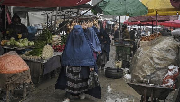 Mujeres vestidas con burka caminan por un mercado en un día frío en Kabul el 19 de enero de 2022. (Foto de Mohd RASFAN / AFP)