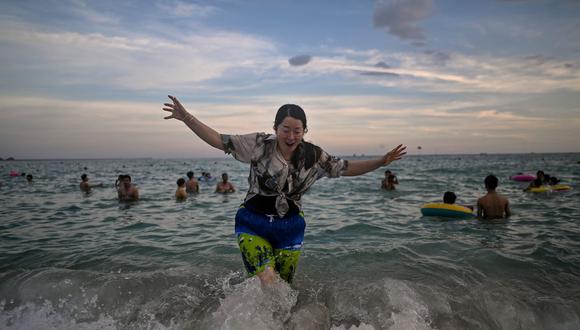 Una mujer se baña en la playa de Dadonghai, en Sanya, en la isla tropical china de Hainan, el 18 de julio de 2021. (Héctor RETAMAL / AFP).