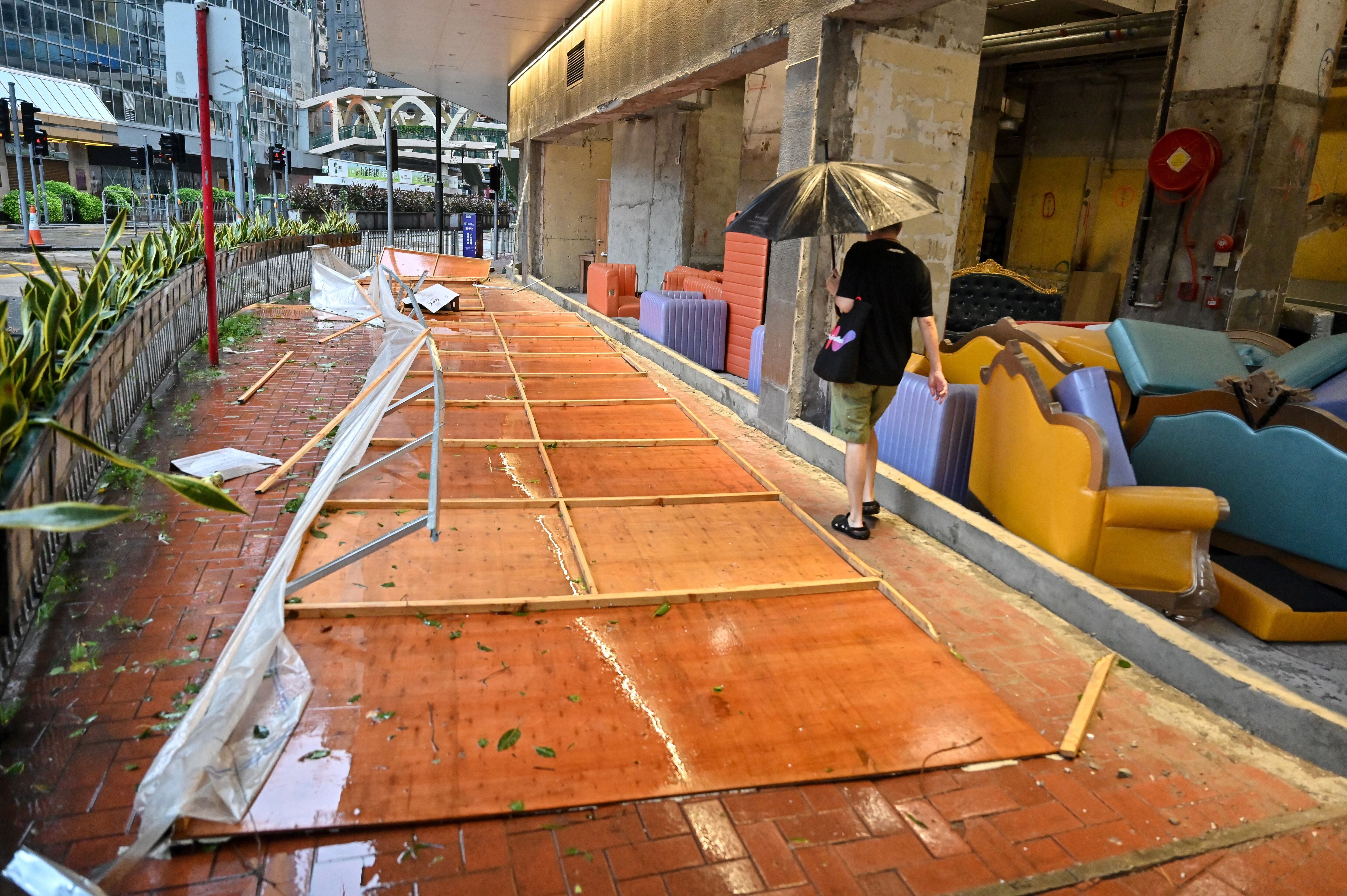 A man walks past the rubble of the protective panels of a furniture store washed away by super typhoon Saola in Causeway Bay in Hong Kong on September 2, 2023. (Photo by Mladen ANTONOV/AFP)