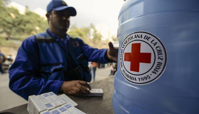 Miembros de la Cruz Roja Venezolana distribuyen bidones de agua y tabletas de purificación de agua en el vecindario de Caricuao en Caracas. (Foto: AFP)