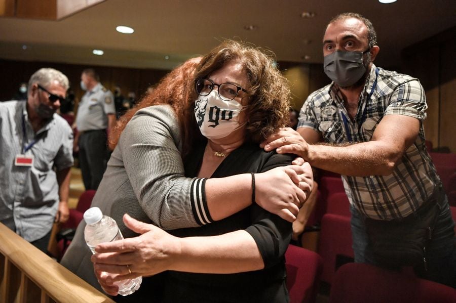 Magda Fyssa, la madre del cantante asesinado Pavlos Fyssas, es abrazada por su hija Irini tras el veredicto contra la agrupación neonazi Amanecer Dorado. (Foto de LOUISA GOULIAMAKI / AFP).