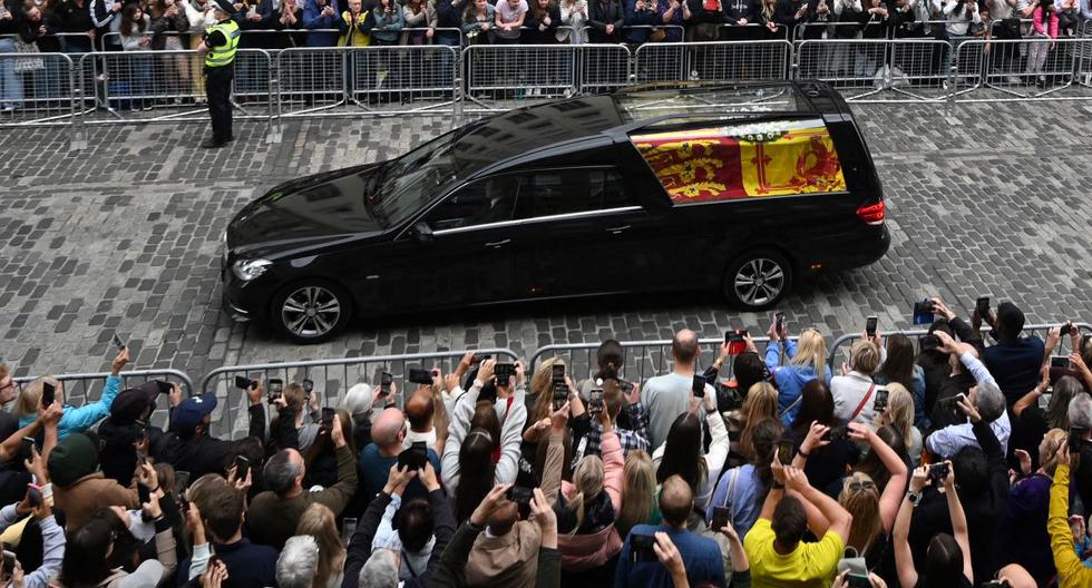 El público observa el coche fúnebre que lleva el ataúd de la reina Isabel II, envuelto en el estandarte real de Escocia, mientras avanza a través de Edimburgo hacia el Palacio de Holyroodhouse, el 11 de septiembre de 2022. (Oli BUFANDA / AFP).