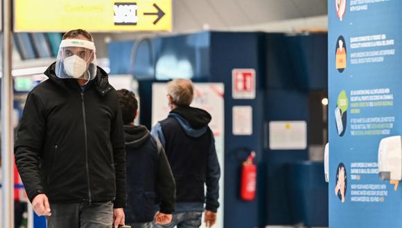 Un pasajero que lleva una mascarilla y un protector facial cruza una terminal el 9 de diciembre de 2020, en el aeropuerto de Fiumicino de Roma. (ANDREAS SOLARO / AFP).
