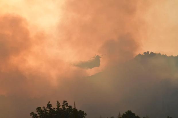 An aircraft drops water during a forest fire in ancient Olympia, western Greece, on Thursday, August 5, 2021. (Giannis Spyrounis / ilialive.gr via Globe Live Media).