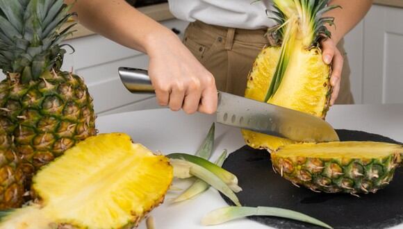 Chef pelando la piña y cortándola en pedazos. (Imagen: SHVETS production / Pexels)