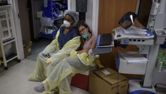 Una trabajadora de la salud duerme y se apoya en su colega para descansar fuera de la Unidad Covid-19 en el United Memorial Medical Center en Houston, Texas. (Foto de Mark Felix / AFP).
