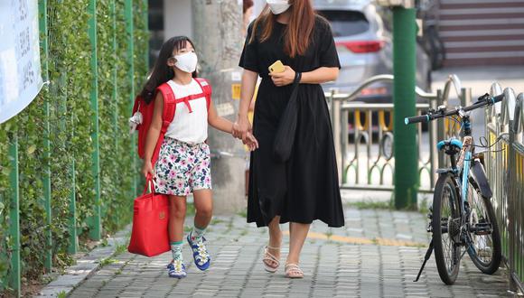 Una madre y su hija caminan a una escuela primaria en Seúl, en una foto de archivo de agosto pasado de 2020. (STR / YONHAP / AFP)