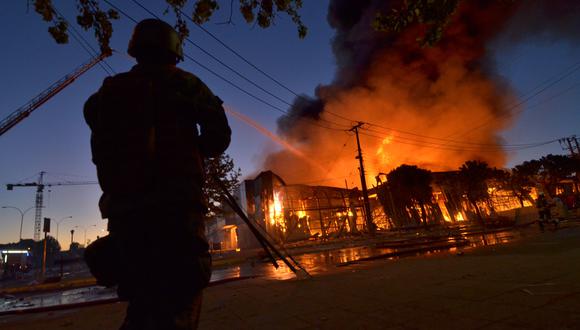 Unidades del cuerpo de bomberos de Chile se encontraban trabajando para controlar las llamas y los vecinos al centro comercial fueron evacuados ante el peligro inminente de propagación. (AFP)