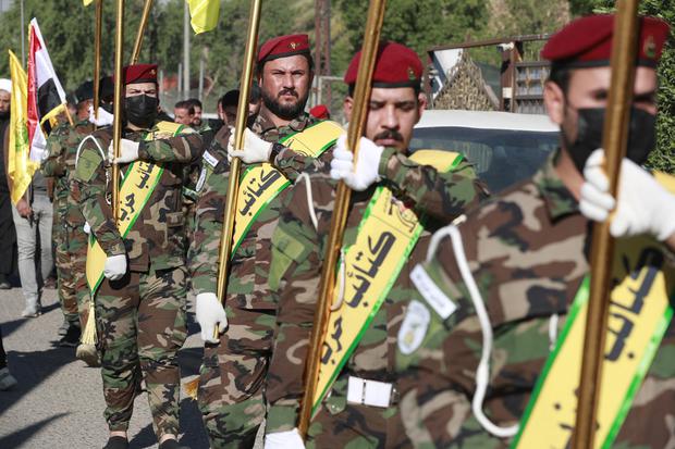 Los combatientes levantan banderas de Irak y de grupos paramilitares, incluidos al-Nujaba y Kataib Hezbollah, durante un funeral en Bagdad, el 4 de diciembre de 2023. . (Foto de AHMAD AL-RUBAYE / AFP).