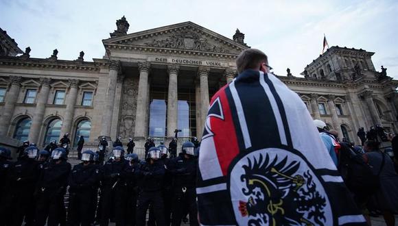 Manifestantes se paran frente al edificio del Reichstag después de intentar subir las escaleras durante una protesta contra las regulaciones para frenar la pandemia de coronavirus en Alemania. (EFE / EPA / CLEMENS BILAN).