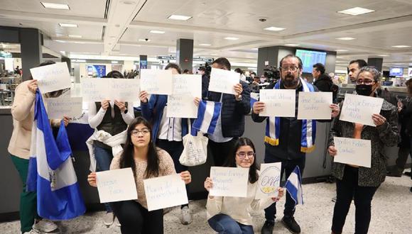 Varias personas sostienen hojas con los nombres de los presos políticos nicaragüenses, expulsados de su país, mientras esperan su llegada el 9 de febrero de 2023 en el aeropuerto de Dulles, Virginia, EE. UU. (Foto de Octavio Guzmán / EFE)