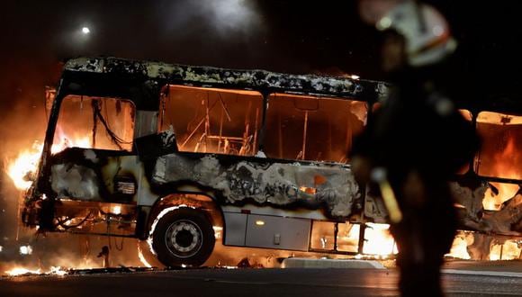 Un policía está cerca de un autobús en llamas mientras los partidarios del presidente de Brasil, Jair Bolsonaro, protestan por la orden de arresto del líder indígena José Acacio Serere Xavante, el 12 de diciembre de 2022. (REUTERS/Ueslei Marcelino).