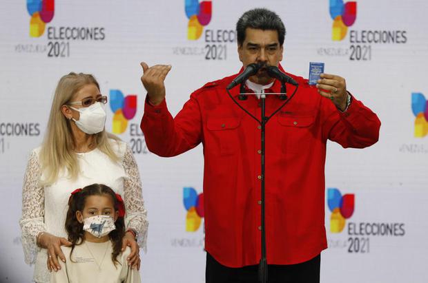 Accompanied by his granddaughter and first lady Cilia Flores, left, Venezuelan President Nicolás Maduro shows a copy of the Venezuelan constitution as he speaks after casting his vote during Venezuela's regional elections, at the Simón Rodríguez Bolivarian Ecological School in the Fuerte Tiuna neighborhood of Caracas, Venezuela, Sunday, November 21, 2021. (AP Photo / Javier Vegas).