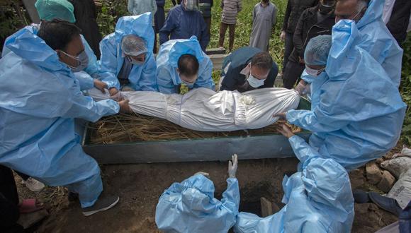 Personal con equipo de protección entierra a una víctima de coronavirus Covid-19 durante un funeral en Srinagar, India, el 7 de mayo de 2021 (Foto de Abid Bhat / AFP)..