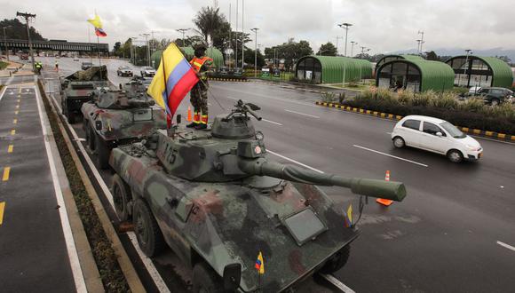 Un soldado iza una bandera colombiana en un tanque del Ejército en las afueras de Bogotá el 4 de mayo de 2021.. (Foto de DANIEL MUNOZ / AFP).