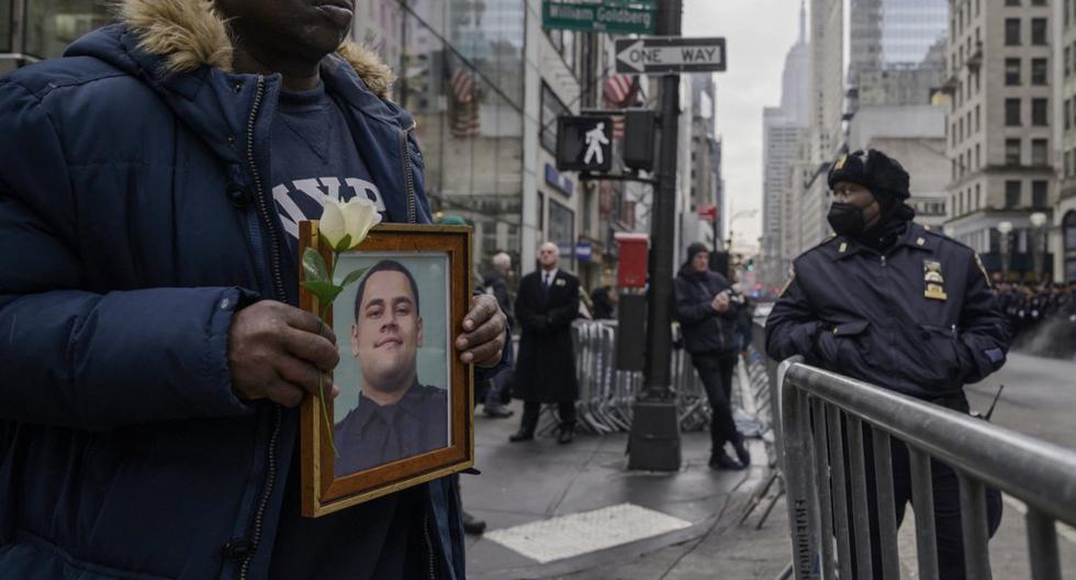 Un hombre sostiene el retrato de Wilbert Mora, uno de los dos policías que fueron asesinados al responder a una llamada de emergencia en el barrio de Harlem, en Nueva York. El caso ha conmocionado a la sociedad y agravado la percepción de inseguridad en la Gran Manzana. (Foto: Ed Jones / AFP)