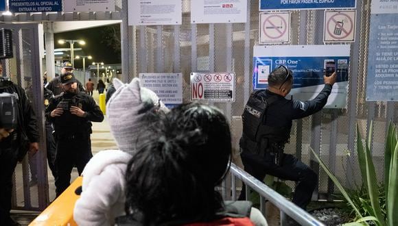 Un oficial de policía local escanea el código QR de la aplicación CBP One en la frontera entre Estados Unidos y México, visto desde Tijuana, estado de Baja California, México, el 11 de mayo de 2023. (Foto referencial de Guillermo Arias / AFP)