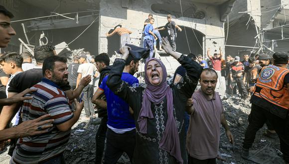 Una mujer palestina reacciona mientras otros se apresuran a buscar víctimas entre los escombros de un edificio tras un ataque israelí en Khan Yunis, en el sur de la Franja de Gaza, el 17 de octubre de 2023. (Foto de Mahmud JAMONES / AFP)