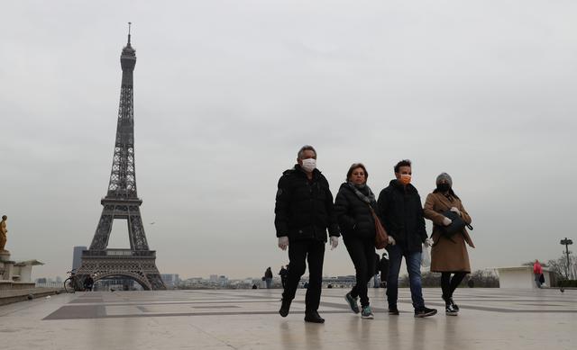 Turistas con máscara protectora contra el coronavirus caminan frente a la torre Eiffel en París, Francia. (AFP / Ludovic Marin).