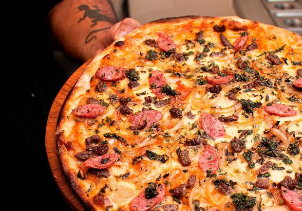 There are 26 artisan pizzas made in a stone oven.  La Parrillera (pictured) has sauteed chunks of meat, smoked bacon, smoked barbecued chorizo, chicken chorizo, house barbecue sauce and oregano.  (Pizzarte)