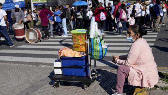 Una vendedora de frutas se sienta en una acera mientras espera clientes durante una manifestación en reclamo de más empleo y asistencia social en Buenos Aires, Argentina, el miércoles 13 de abril de 2022. (AP Foto/Natacha Pisarenko).
