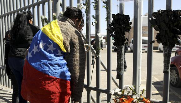 Migrantes venezolanos depositan una ofrenda floral durante una protesta frente a un centro de detención de inmigrantes en Ciudad Juárez, estado de Chihuahua, México, el 28 de marzo de 2023. (Foto de HERIKA MARTINEZ / AFP)