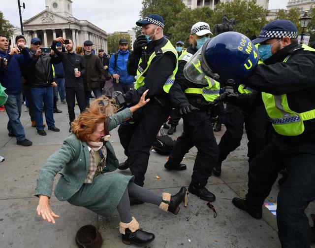 Una mujer cae mientras la policía del Reino Unido trata de dispersar una protesta en Londres contra las restricciones impuestas por el coronavirus. (Foto: JUSTIN TALLIS / AFP).
