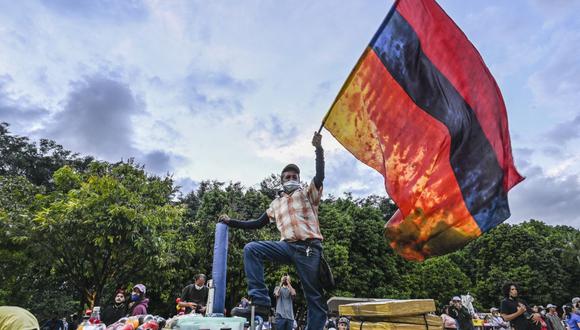 Un manifestante ondea una bandera colombiana colocada al revés y con sus franjas azules y amarillas teñidas de rojo que representan la sangre, durante una protesta contra el gobierno del presidente Iván Duque en Medellín. (Foto de JOAQUIN SARMIENTO / AFP).