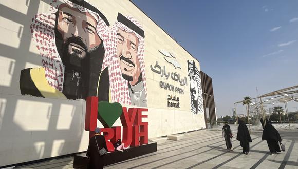 Las mujeres saudíes pasan junto a un mural que representa al rey saudí Salman bin Abdulaziz (centro), el príncipe heredero Mohammed (izquierda) y el rey Abdulaziz bin Saud (derecha), el fundador del moderno Reino de Arabia Saudita, en un parque en la capital Riyadh, el 16 de enero de 2023. (Foto: Giuseppe CACACE / AFP)