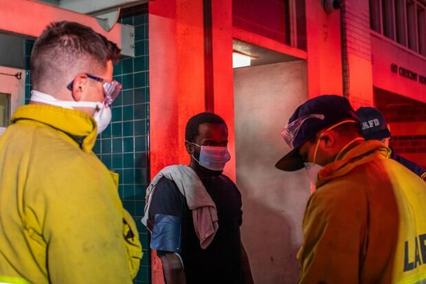 Los paramédicos de LAFD Station No9 hablan con un hombre sin hogar con una máscara facial como medida preventiva contra la propagación del nuevo coronavirus COVID-19, durante la atención médica en Skid Row, en el centro de Los Ángeles, California (Foto: Apu Gomes / AFP)