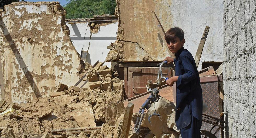 Un niño sostiene una bicicleta dañada que está entre los escombros tras un terremoto en el distrito montañoso de Harnai, Pakistán, el 7 de octubre de 2021. (Banaras KHAN / AFP).